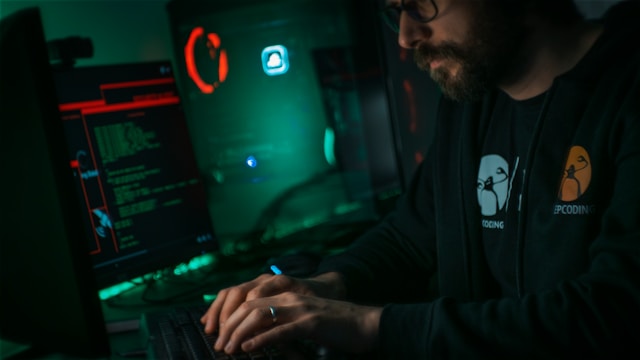 Man in a black jacket hacking a computer server.