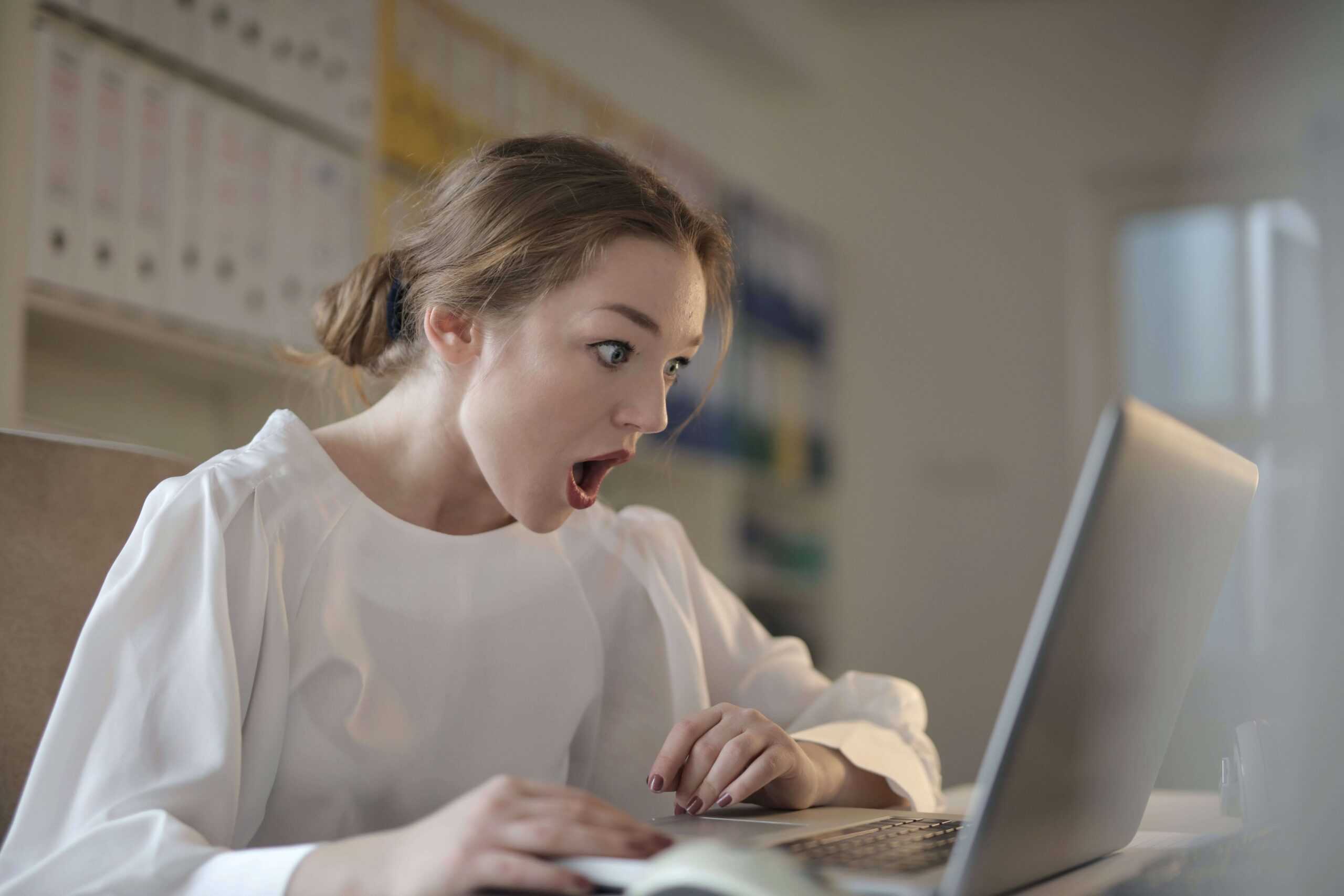 An employee looks at their computer in shock, having just unwittingly become an insider threat.