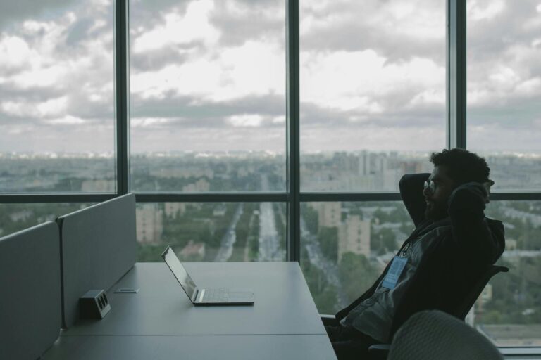 Man relaxing at office desk with city view