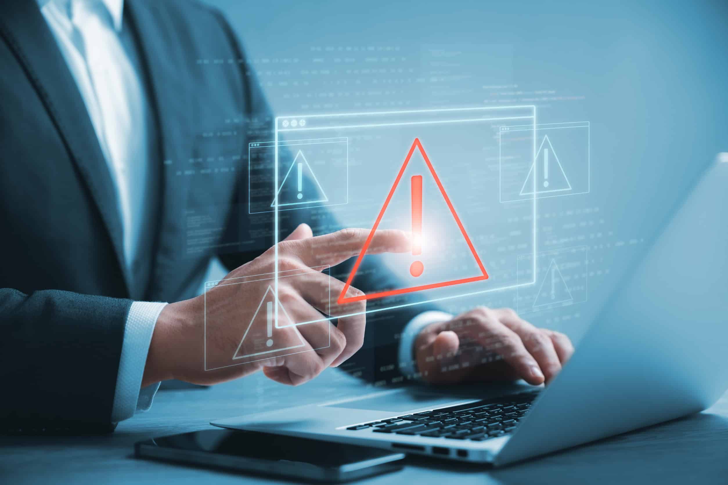 An SMB owner touches a glowing alert above his laptop, symbolizing cybersecurity