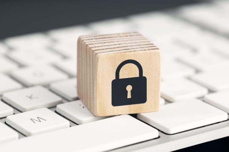 Wooden block with padlock icon on computer keyboard symbolizing cybersecurity