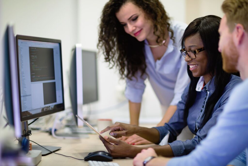 Group of programmers collaborating in front of computer screens