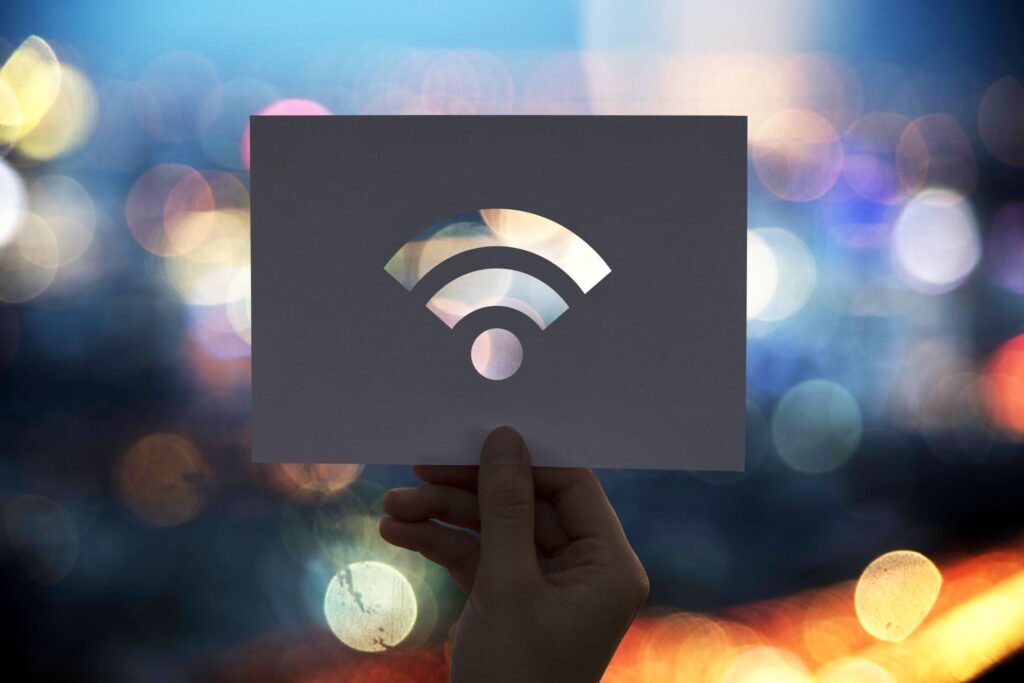Hand holding paper cutout of Wi-Fi symbol with city lights in background
