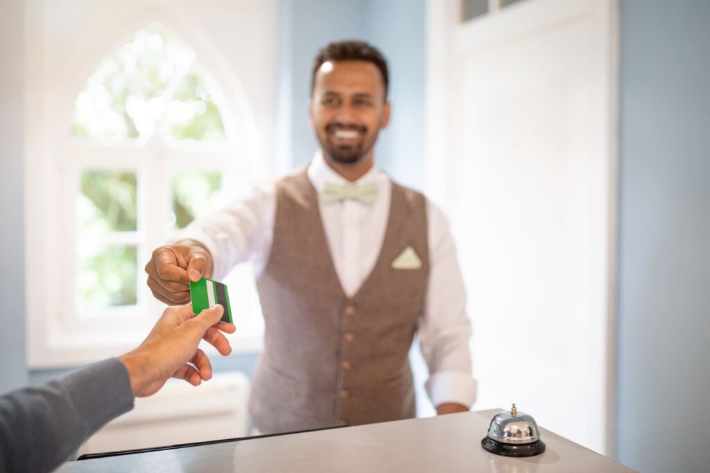 Hotel receptionist handing key card to guest at front desk