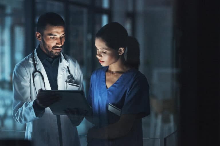 Shot of two young doctors using a digital tablet late at night in a modern hospital