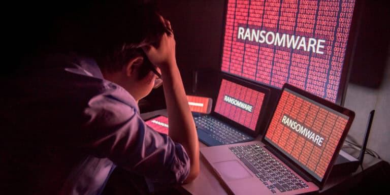 Frustrated young man faces ransomware screen, showing small offices now targeted by cyberattacks.