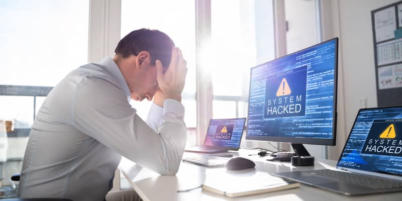 A small business owner anxiously looking at her laptop, concerned after falling victim to a cyberattack.