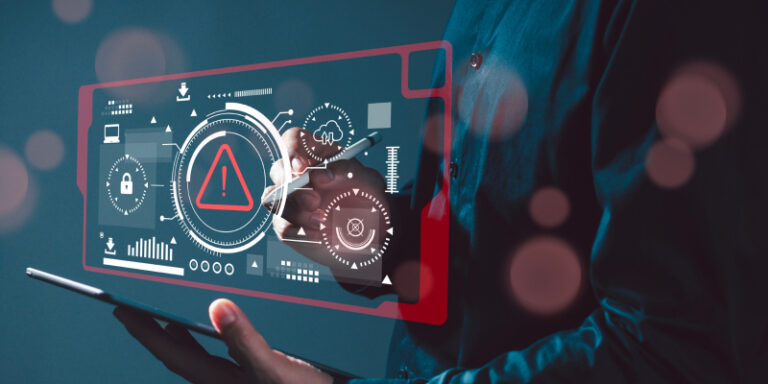 A distressed man sits in front of a laptop displaying a ransomware alert, with a worried expression on his face.
