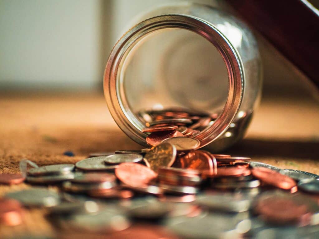A glass jar emptying coins onto a table.
