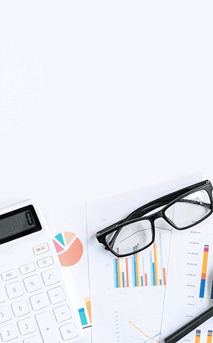Desk with financial documents showing colorful charts and graphs, a white calculator, and a pair of black-framed glasses.