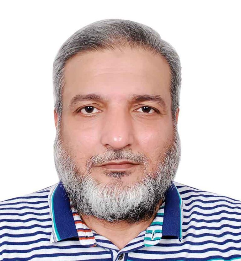 Close-up portrait of a middle-aged man with a gray beard wearing a blue-and-white striped polo shirt, looking at the camera.