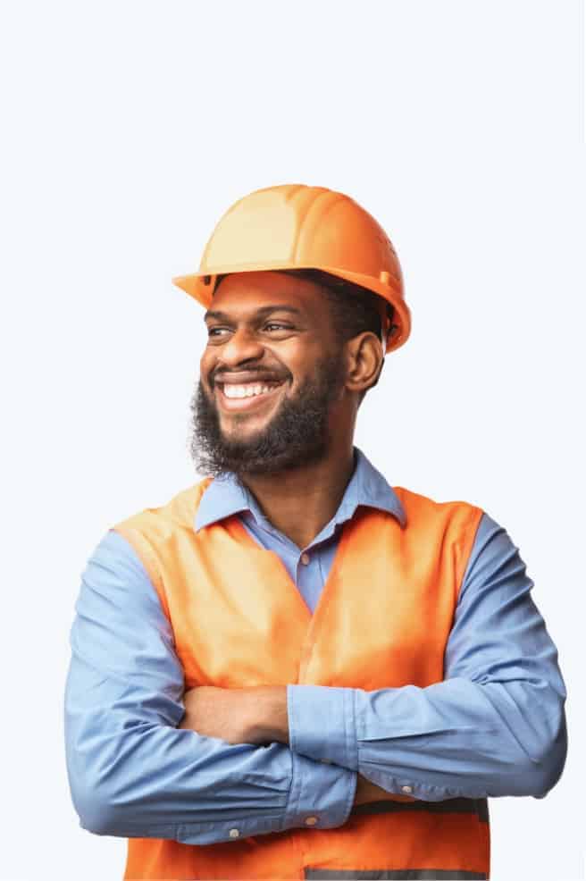 Smiling construction worker in an orange safety vest and hard hat with arms crossed.