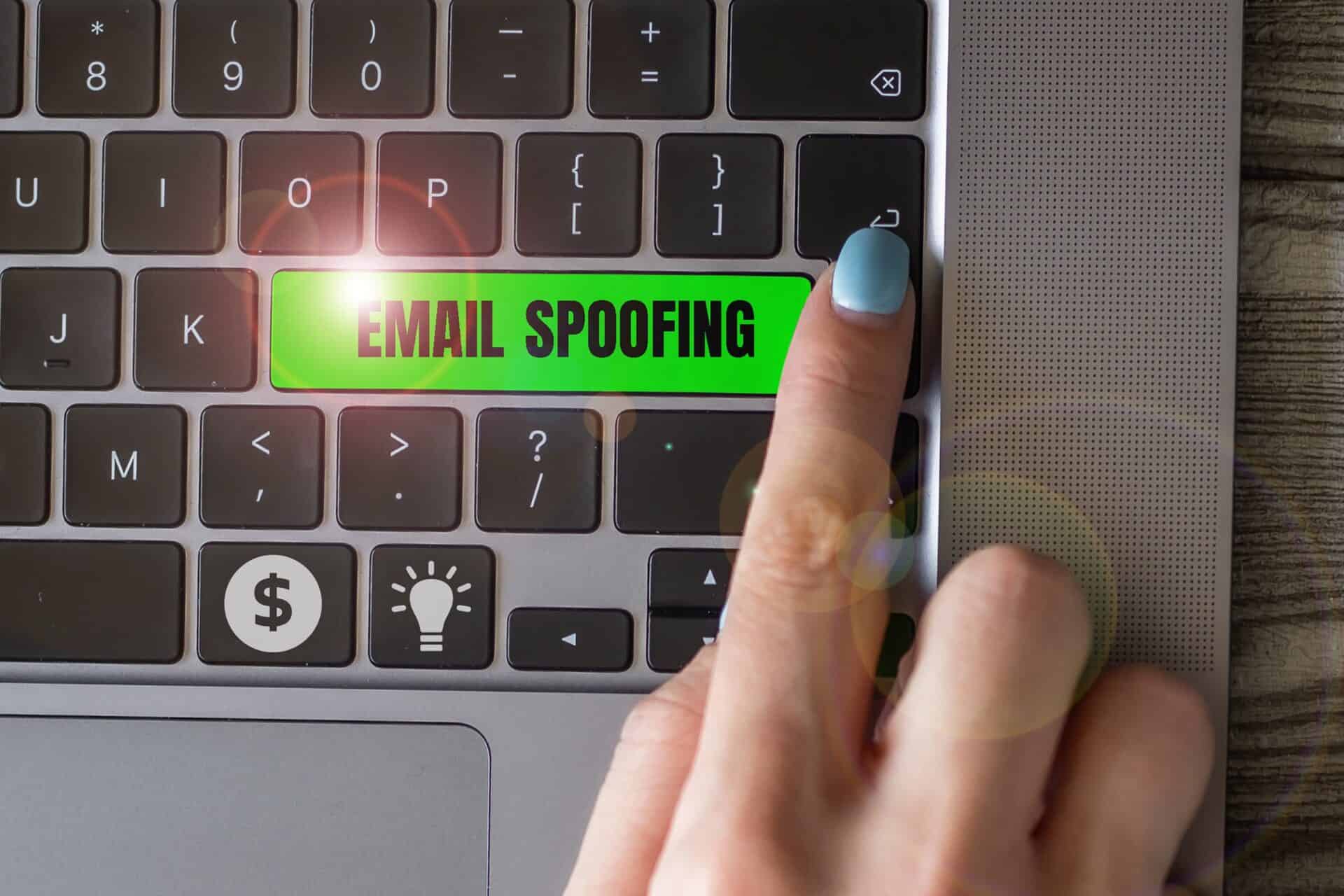 Index finger points at a key with email spoofing written on it.