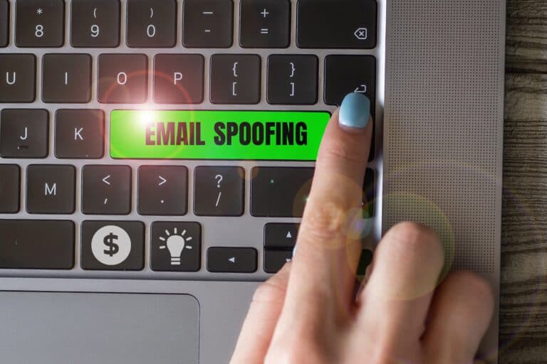 Index finger points at a key with email spoofing written on it.