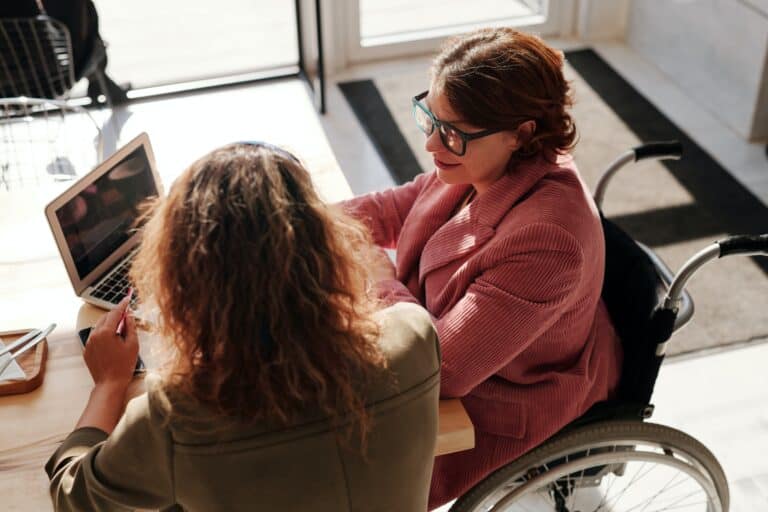 two women sitting next to a laptop during a meeting