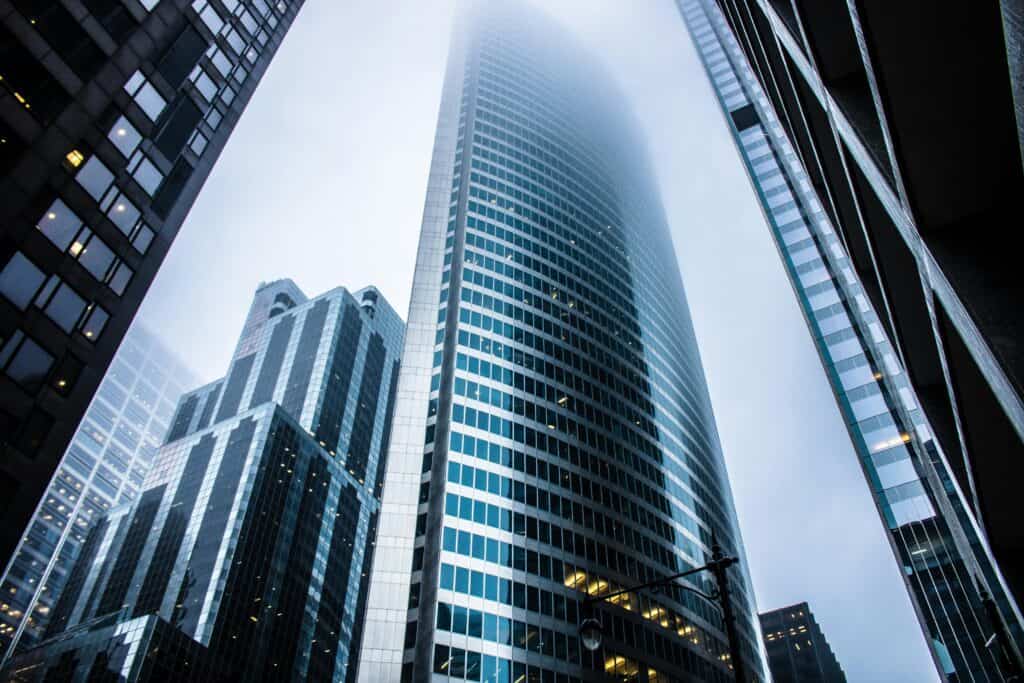 Worm's eye view of skyscraper buildings amidst fog in the city.