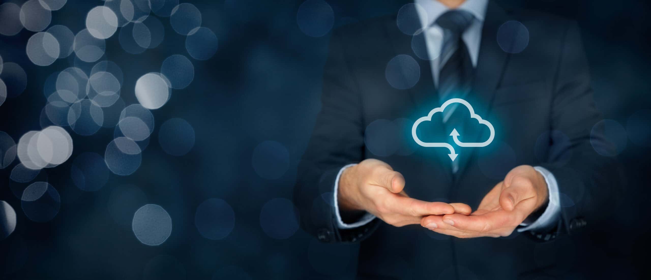 A businessman holds a glowing blue symbol depicting cloud downloading and backup.