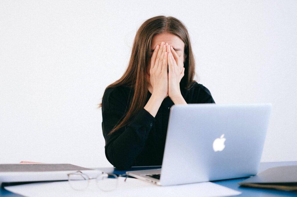 A woman covers her face after seeing on her laptop that her business is dealing with a cyberattack.