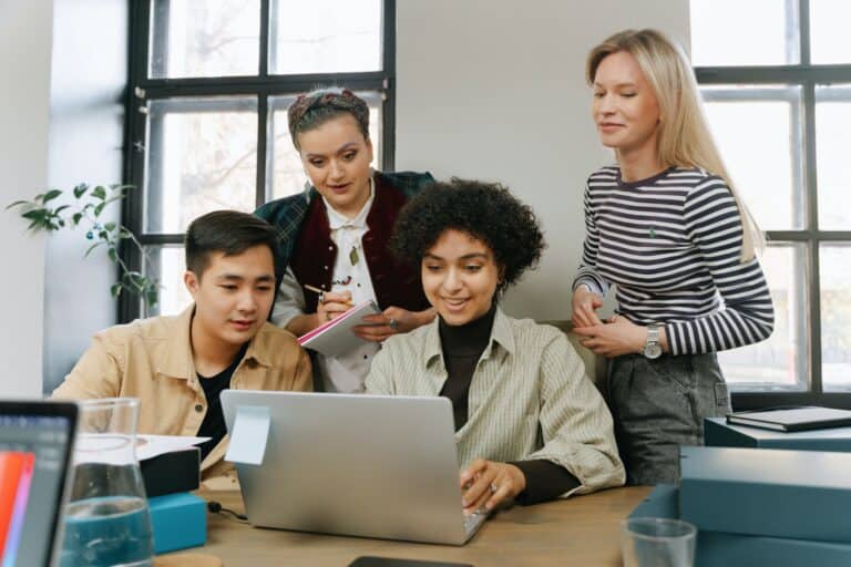 The owner of an SMB shows three employees the new password policies for her business on a laptop.