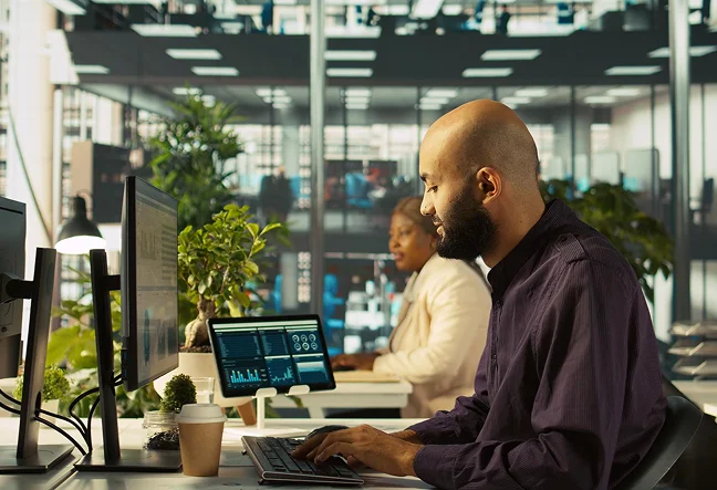 IT professional monitoring cloud services dashboard at desk