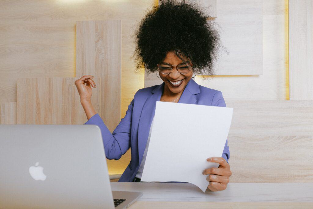 A business owner celebrates as she looks at a piece of paper that says her business is resilient.