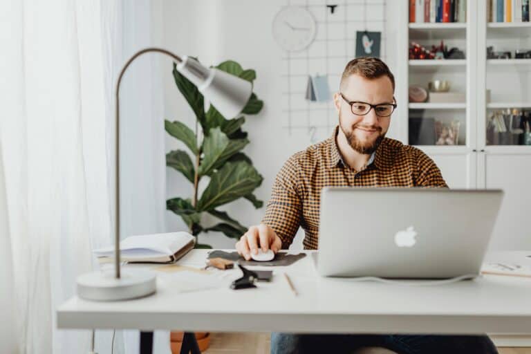 A happy employee uses a productivity app on his Apple laptop.