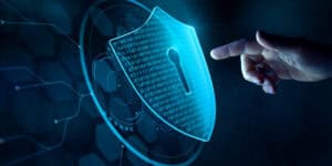 Person touching virtual cybersecurity shield, represents cybersecurity practices at work.