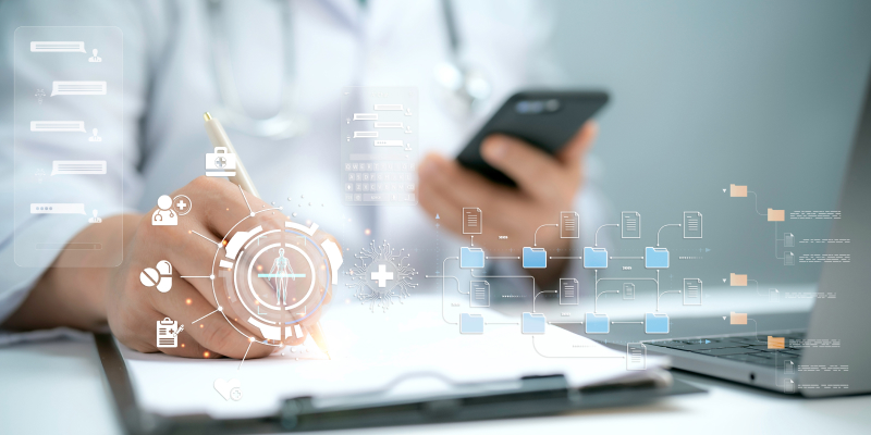 A closeup view of a healthcare professional working with mobile phone and laptop highlight the IT infrastrucure in healthcare industry.