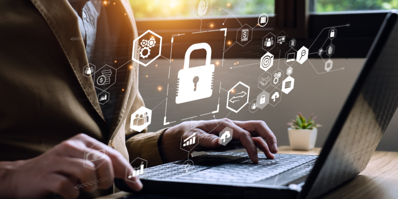 A business owner researches enterprise-grade cybersecurity on his laptop, with security icons displayed on the screen.
