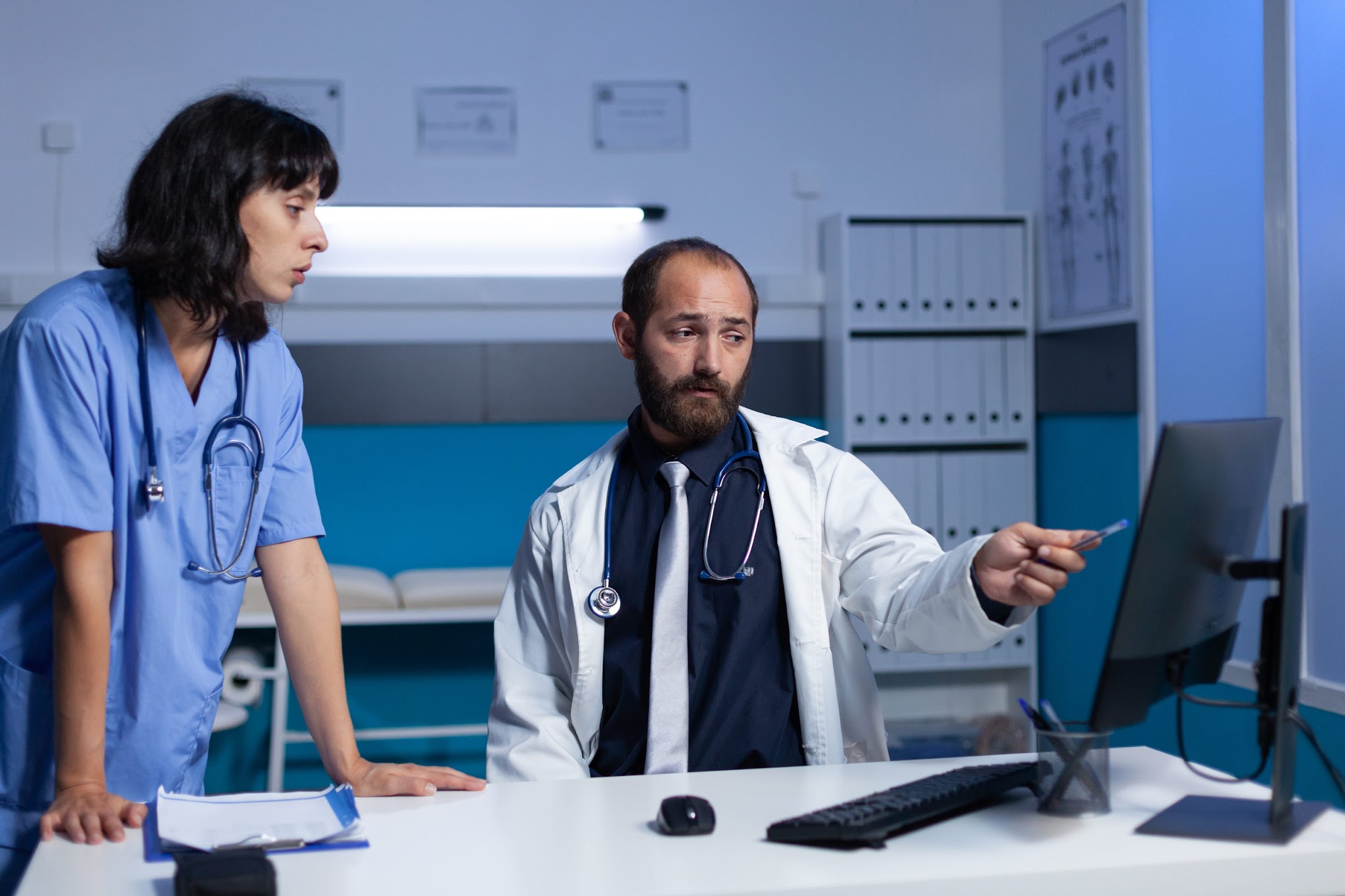 Healthcare professionals reviewing information on a computer screen in a medical office, discussing patient data, compliance requirements, and secure information management.