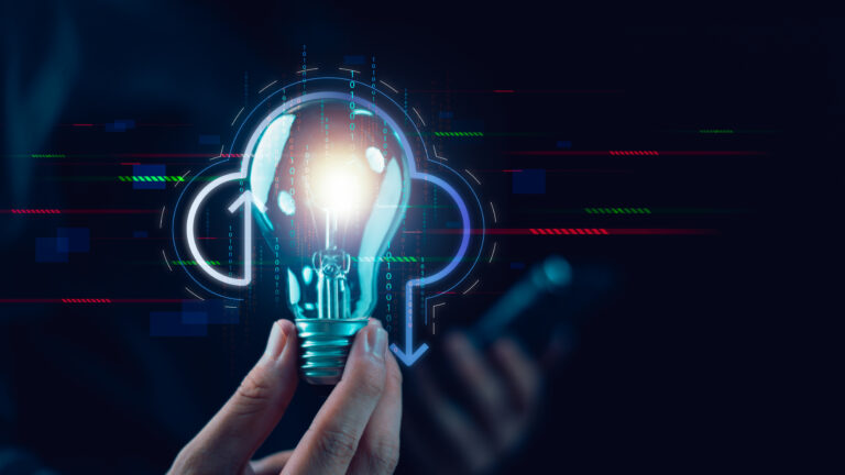Hand holding a lit lightbulb with blue digital holograms and binary data around it, symbolizing innovation and technology.