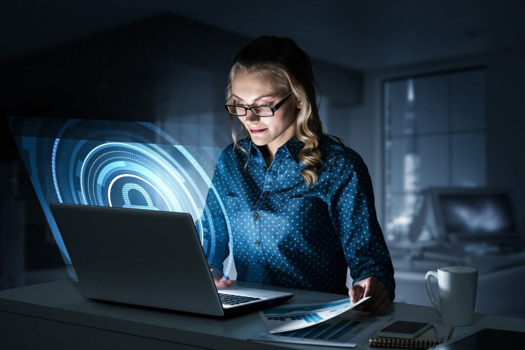 A business owner works on a laptop with a glowing lock over the screen that depicts cybersecurity.