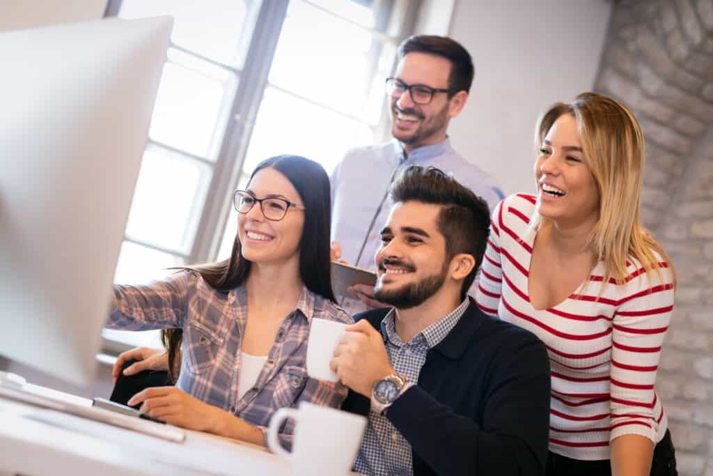 Four coworkers use a single computer to take part in an MFA training meeting.