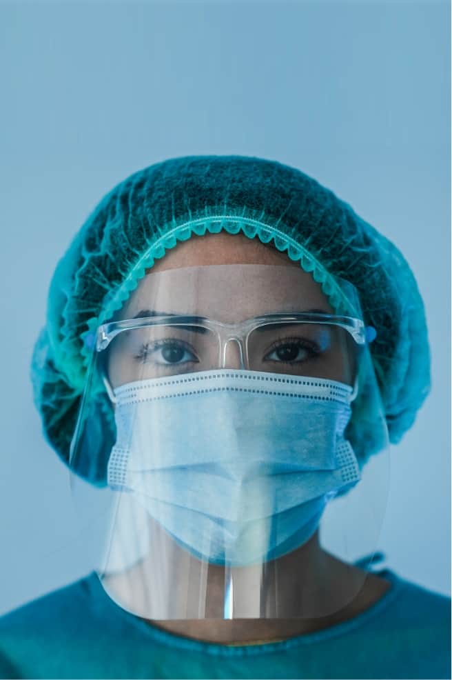 healthcare worker covered with a hair net, mask, and face shield