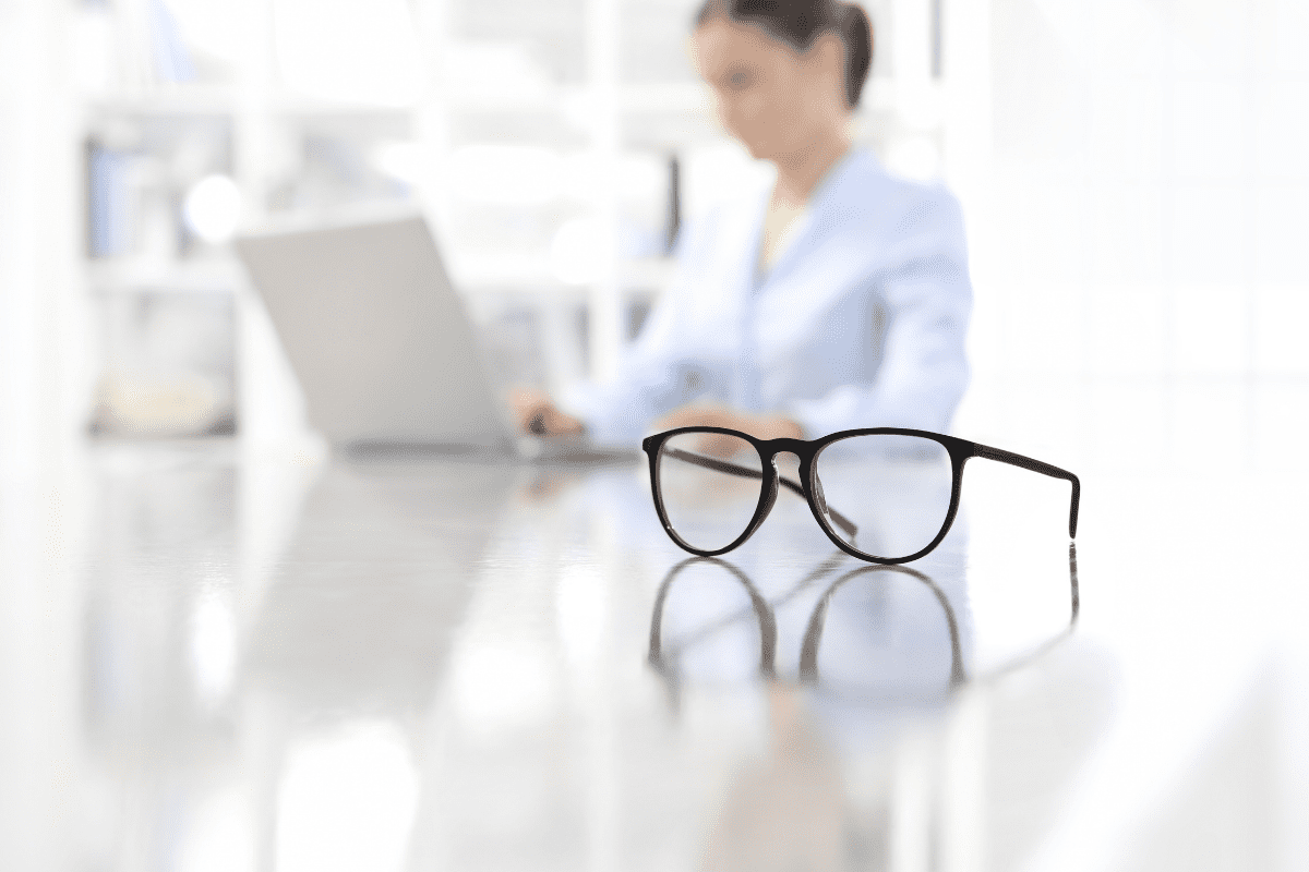 Woman on computer with glasses in foreground
