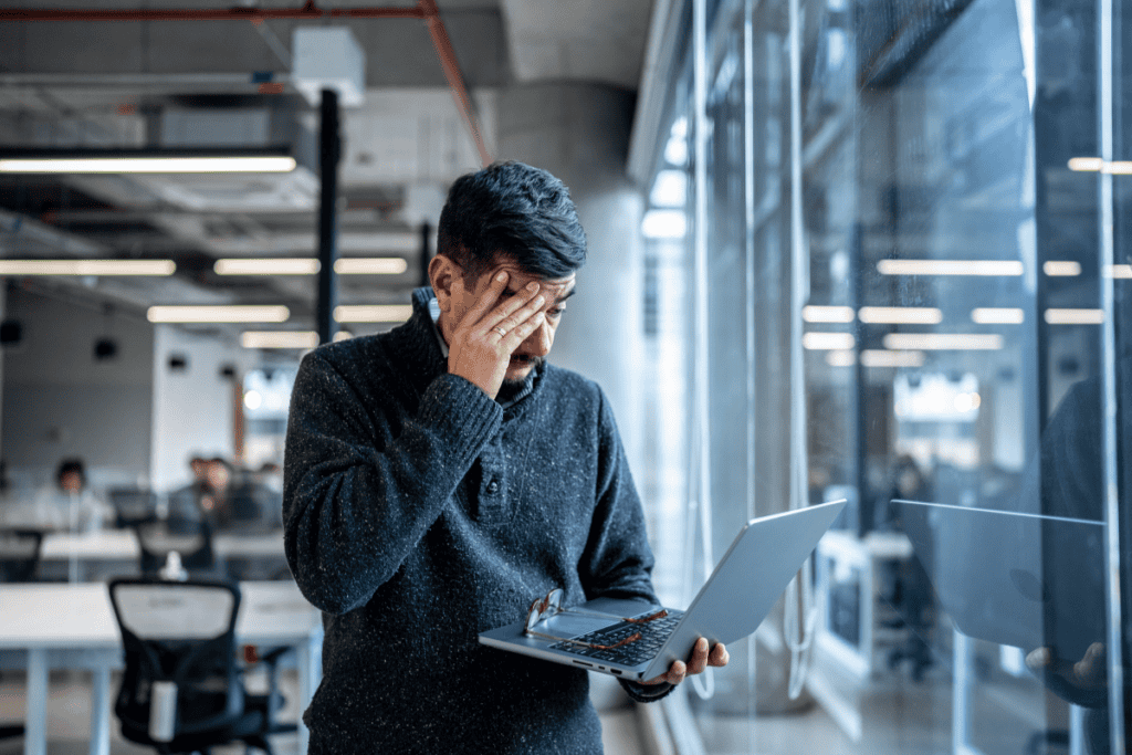 man stresses while holding laptop at work