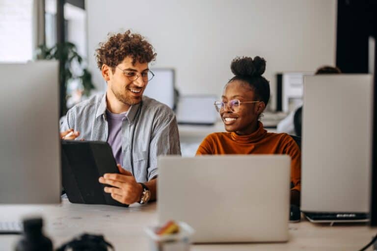 Man and woman in office doing business on their end point devices.