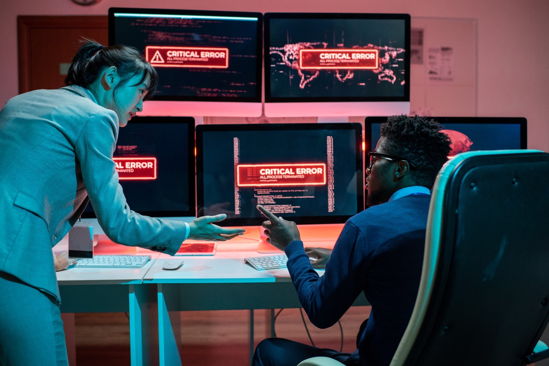 Developers discussing critical error messages across multiple monitors