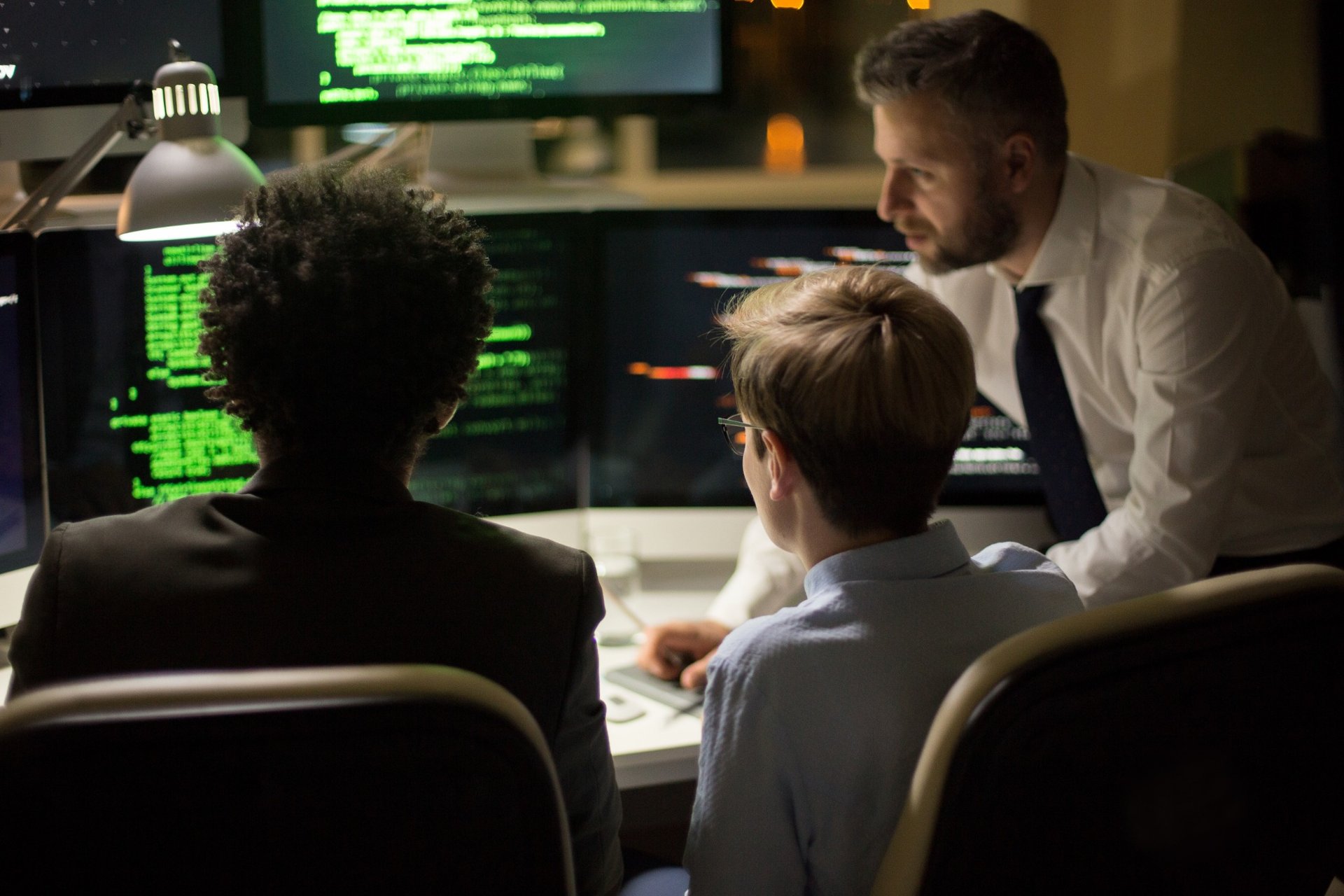 Developers reviewing code on multiple screens late at night