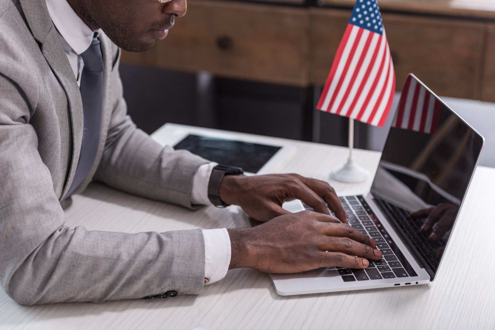 Man working on laptop beside small United States flag