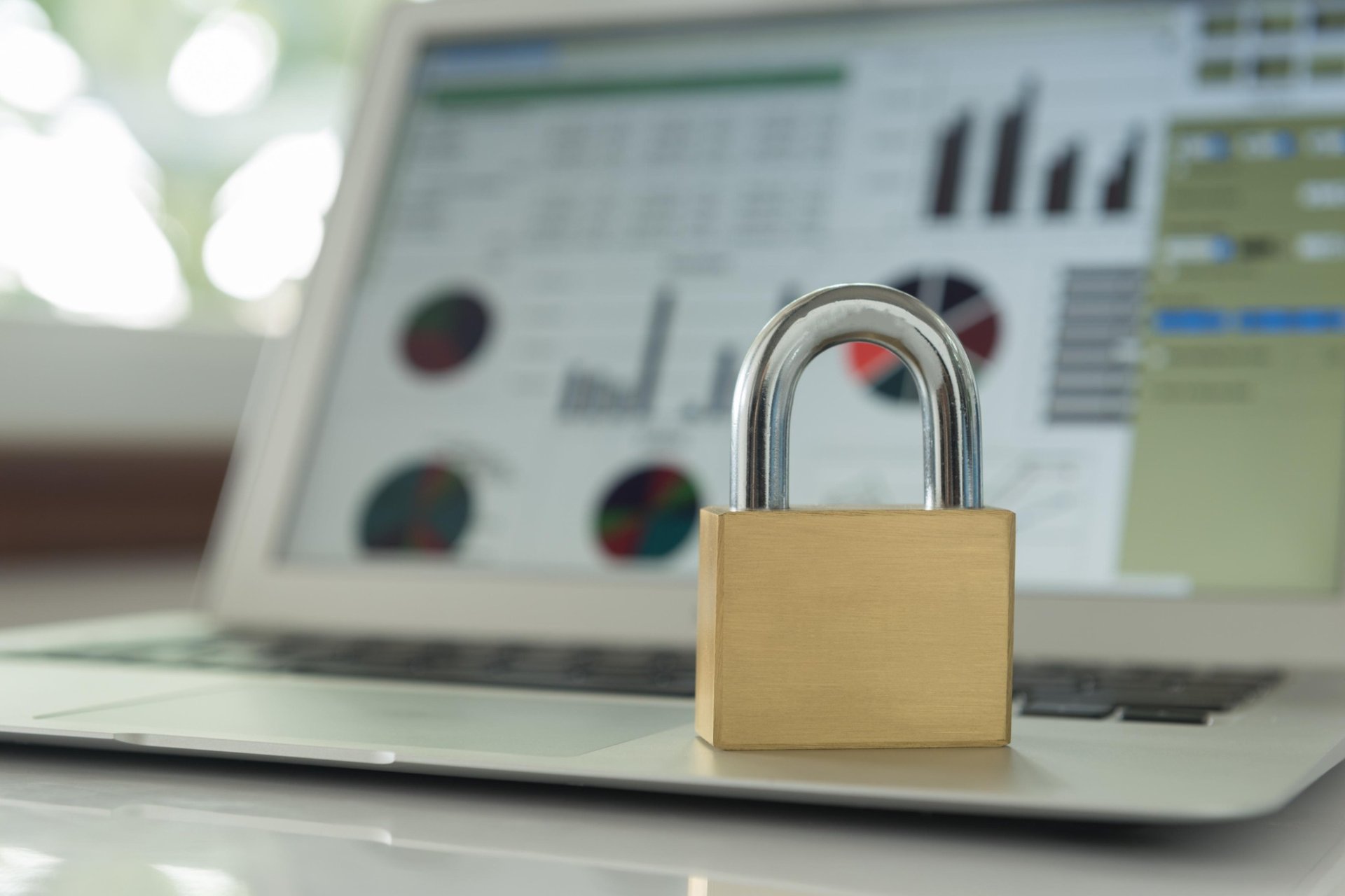 Metal lock on laptop with charts in background