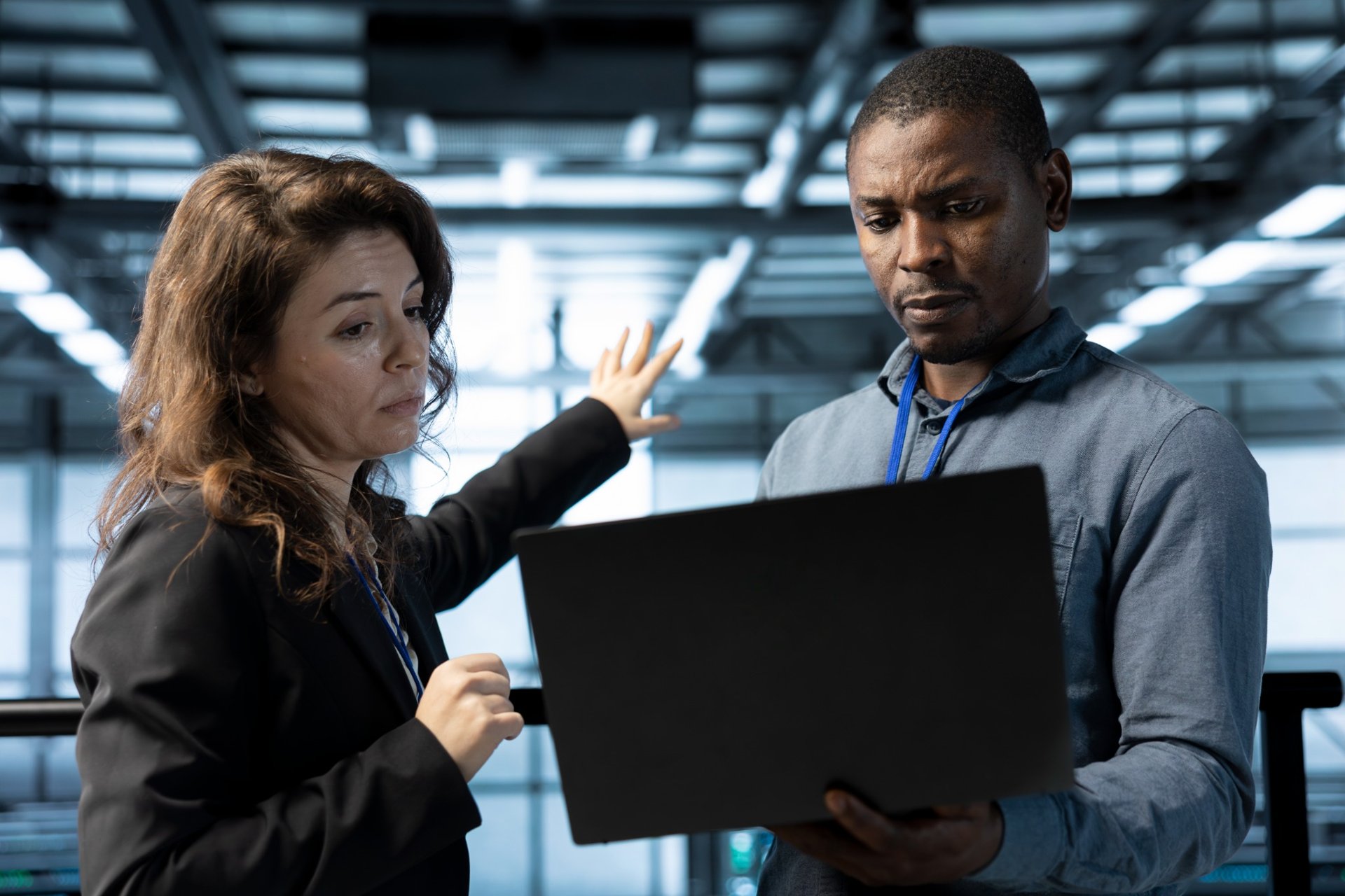 Two professionals reviewing security risks on a laptop inside a data cente