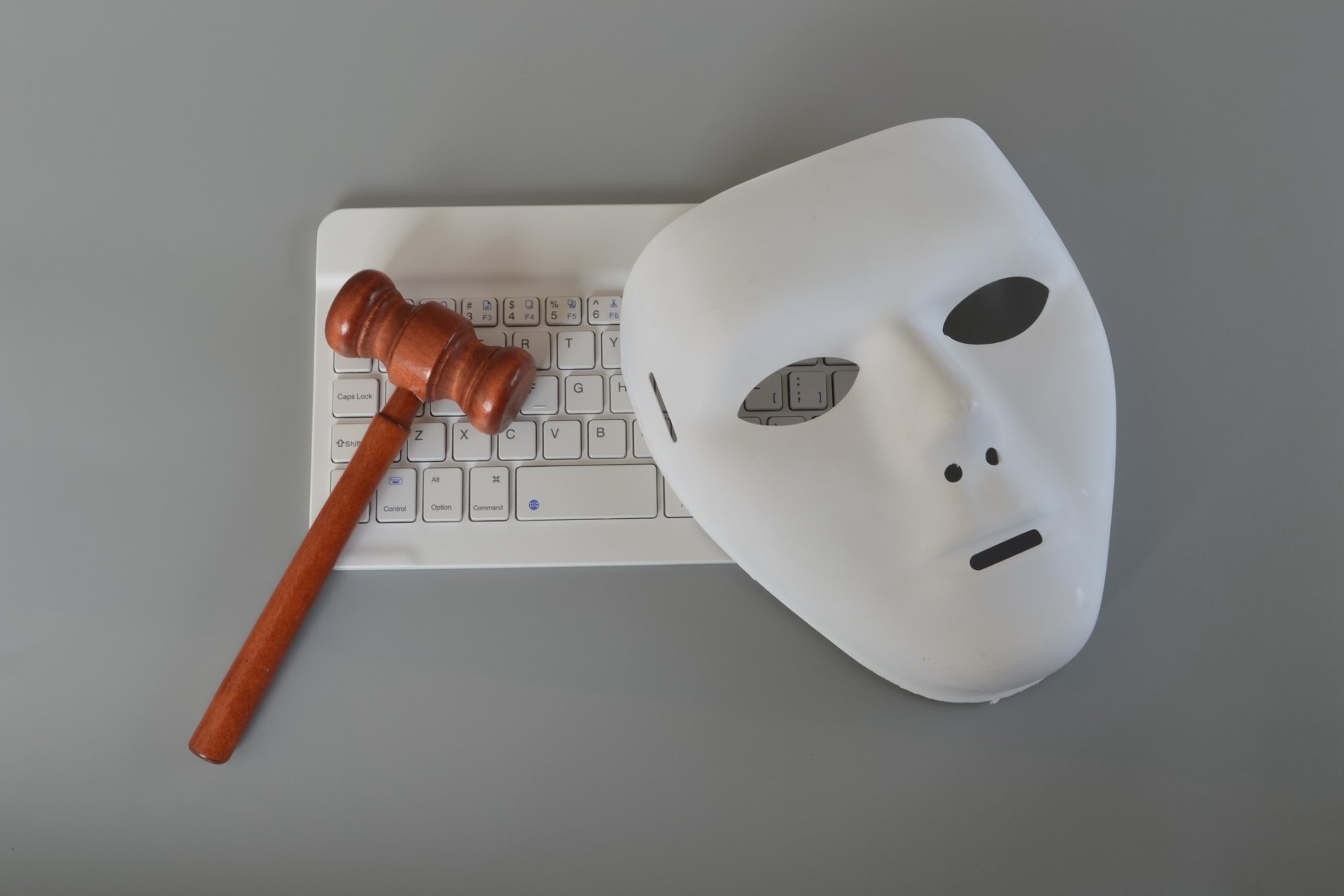 White mask and gavel on keyboard symbolizing cyber law