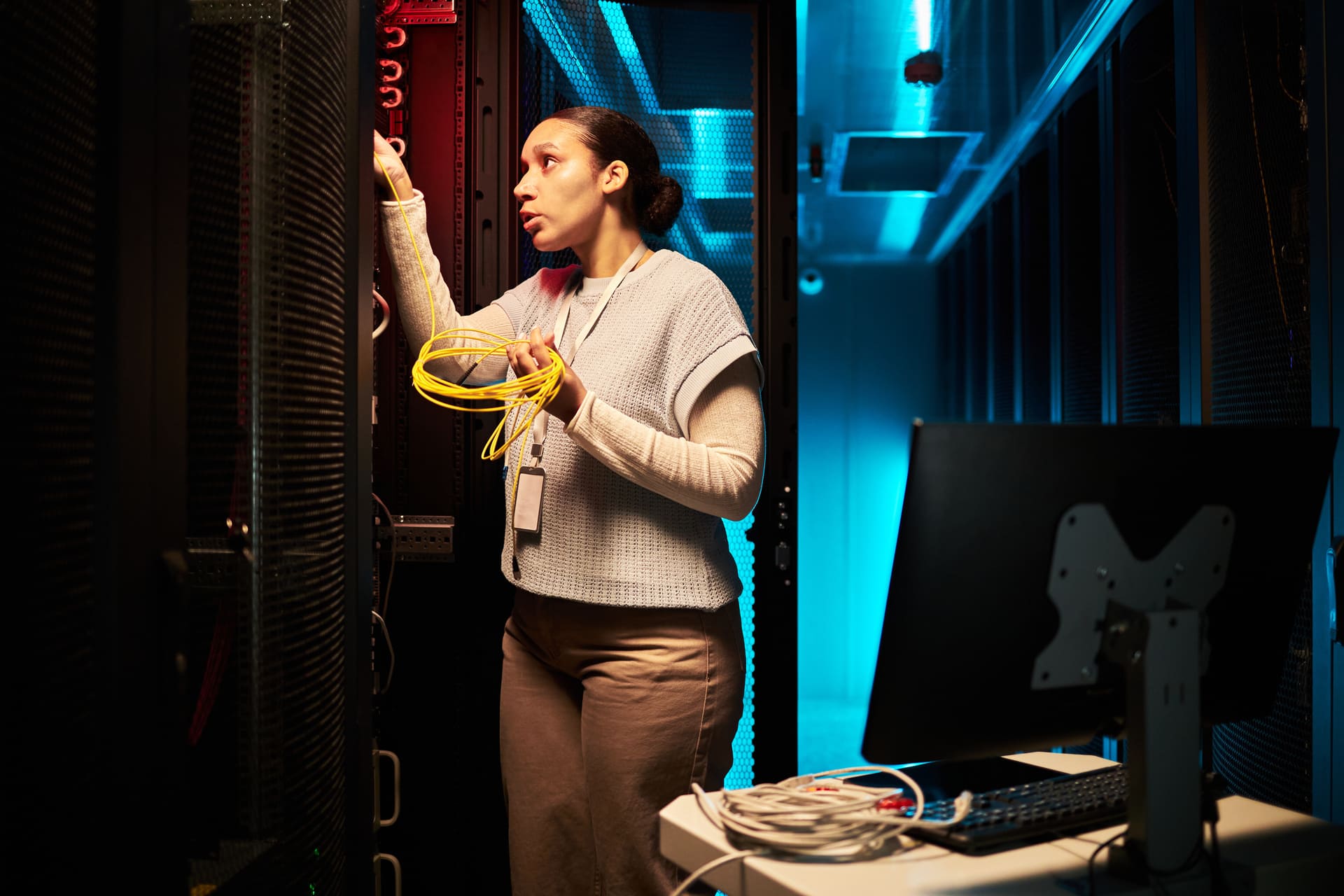 Female technician managing cables in a server room | CMIT Solutions Female technician managing cables in a server room - cyber security