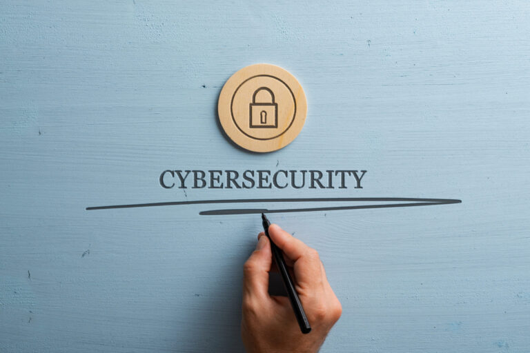 Hand writing the word cybersecurity with a padlock icon above it