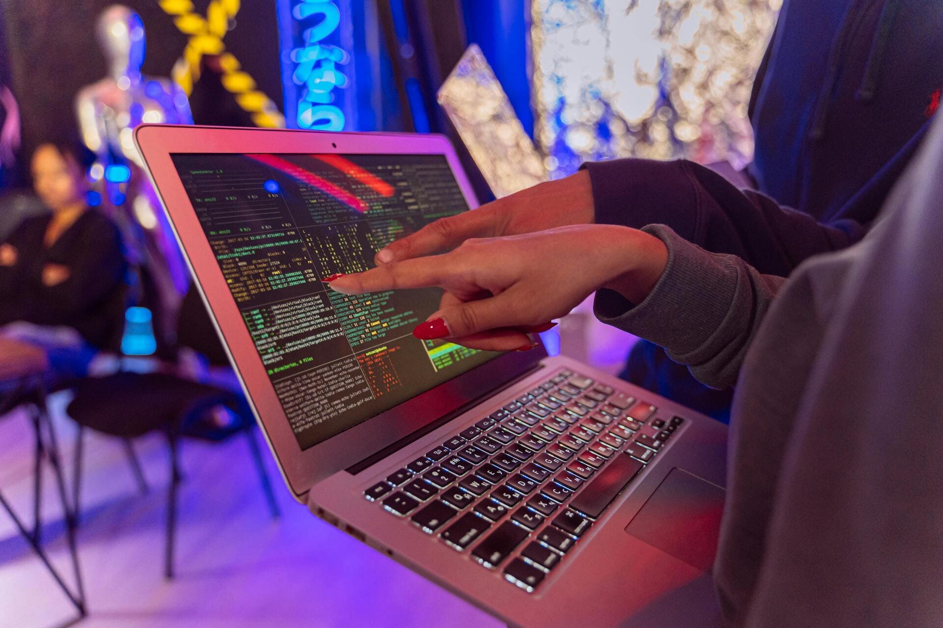 Network Security Threats - Hands pointing at laptop with colorful code