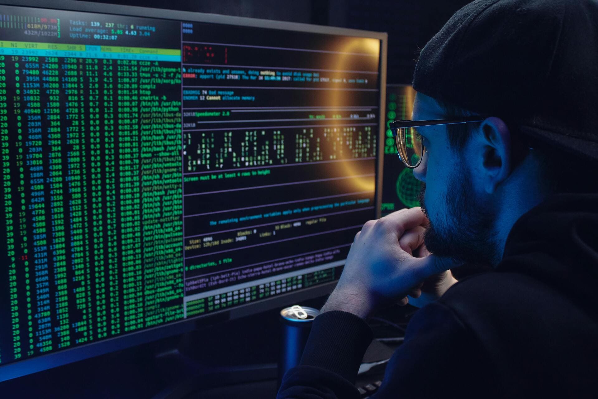 Network Security Threats - Man analyzing code on dual monitors