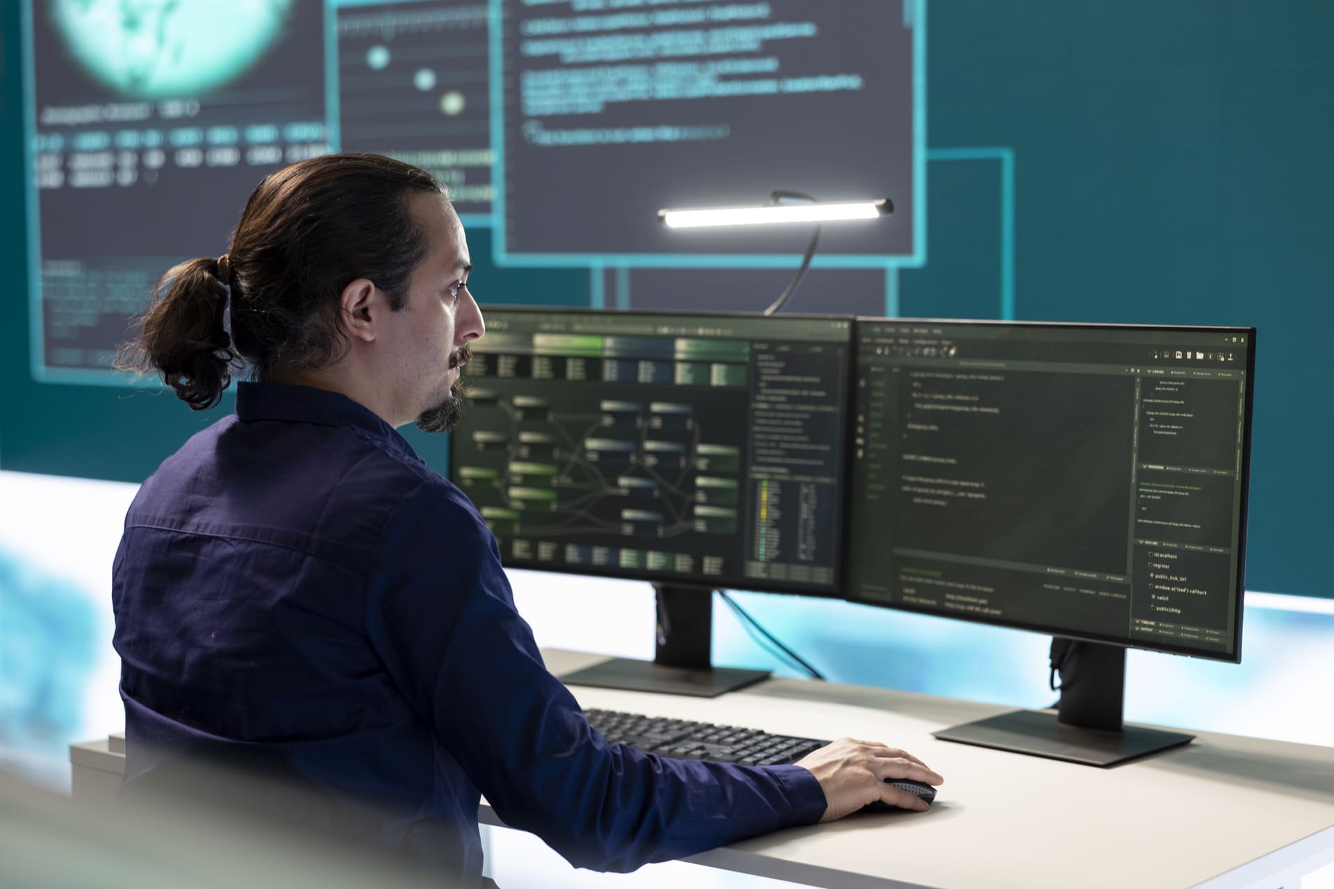 Man monitoring code on multiple screens in a control room