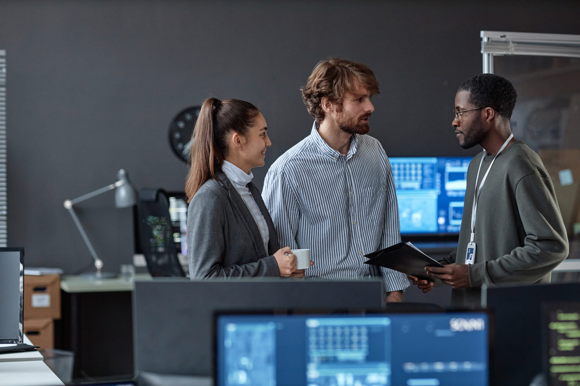 Team talking in a tech office with computer screens around
