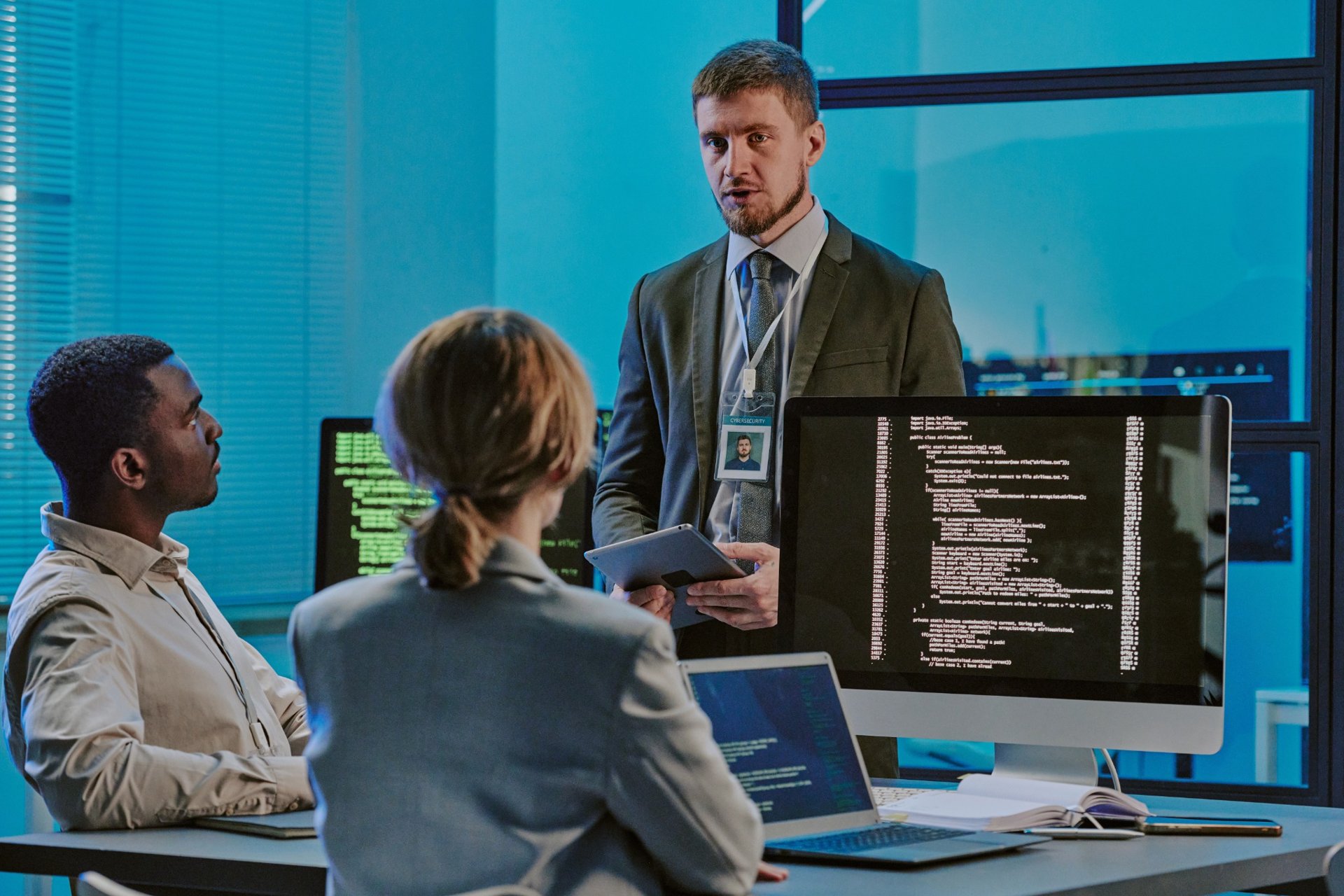 Three professionals in a tech office discussing cybersecurity protocols